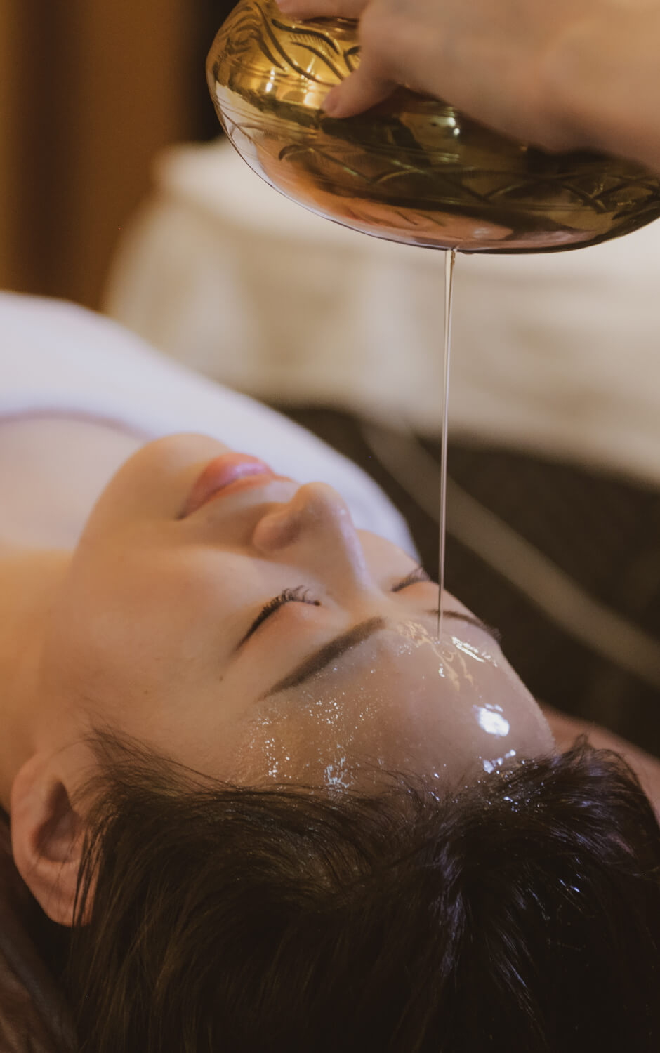 温かいオイルを額に垂らしているシロダーラ体験の様子