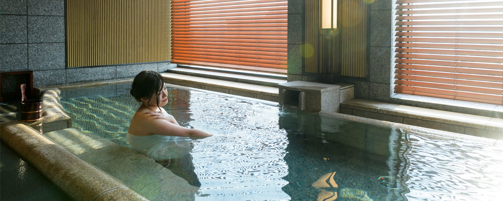 写真:女性が温泉に入る様子